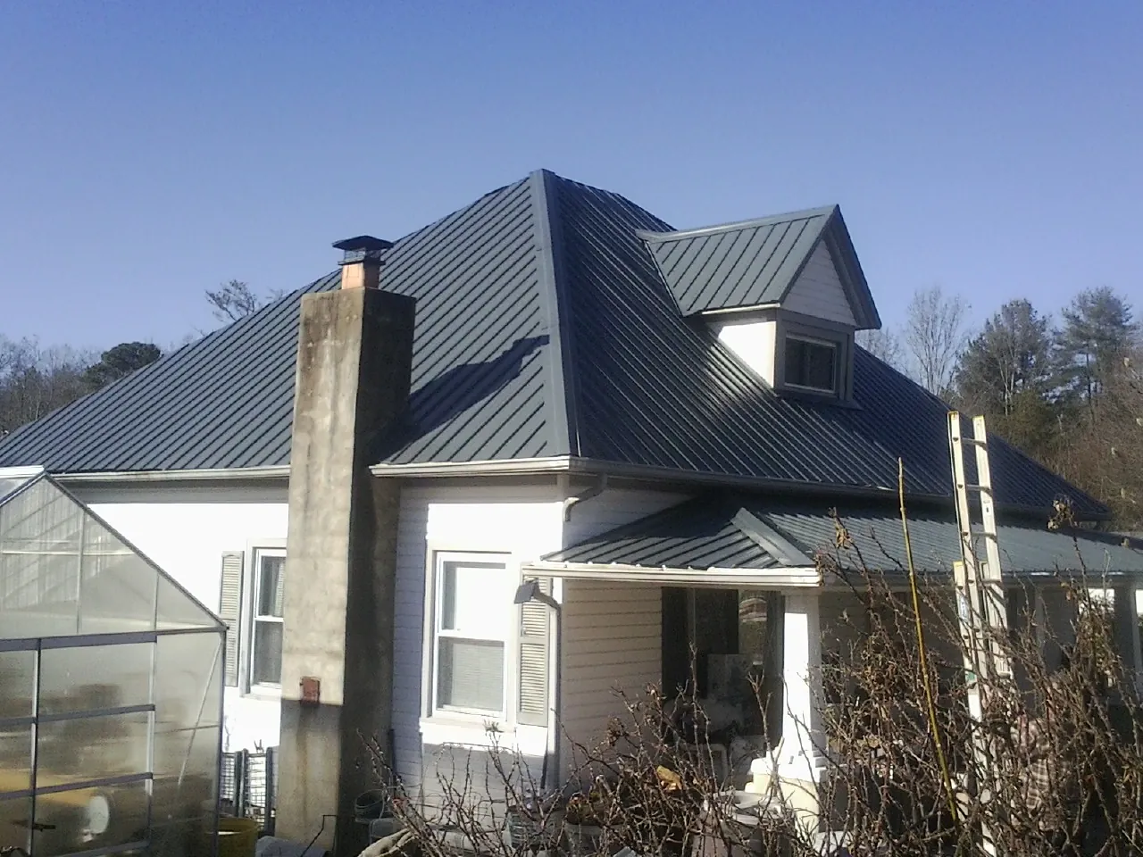 Dark blue standing seam metal roof on a white farmhouse with dormer — Slate & Tile Roof Repair by Roofing Brothers in Thorndale