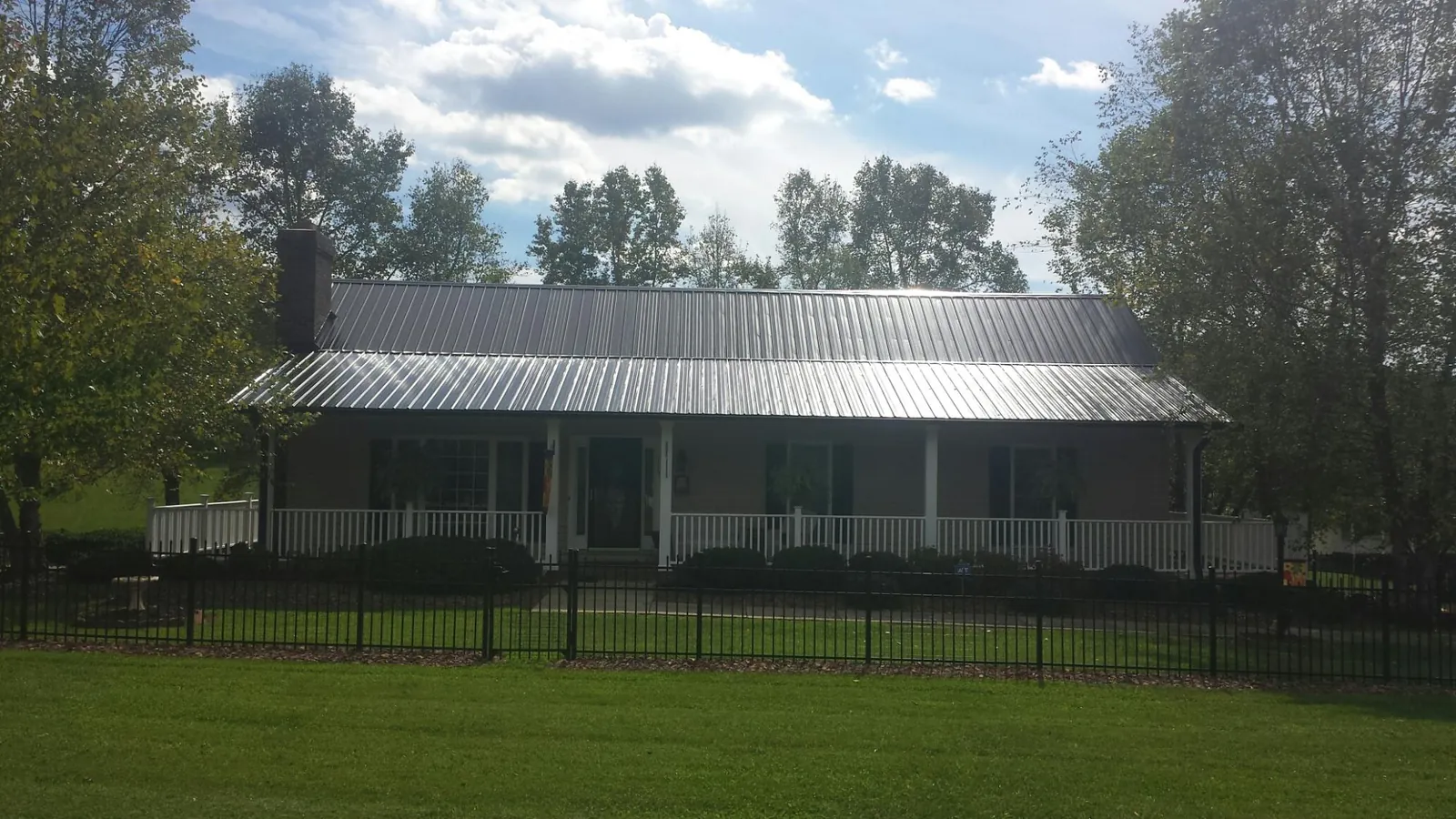 Gray metal roof on a brick ranch with a full width front porch — Gutter Guard Installation work by our crew in Thorndale