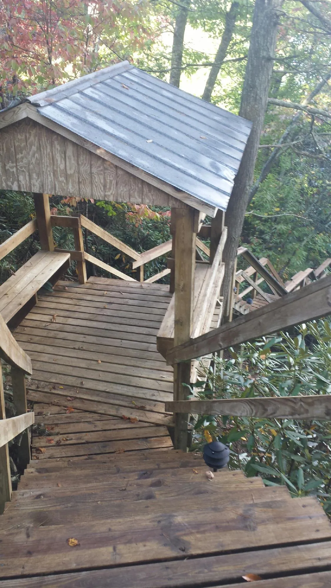 Metal roofed shelter over wooden steps on a wooded walkway — Skylight Repair & Installation work by our crew in Thorndale