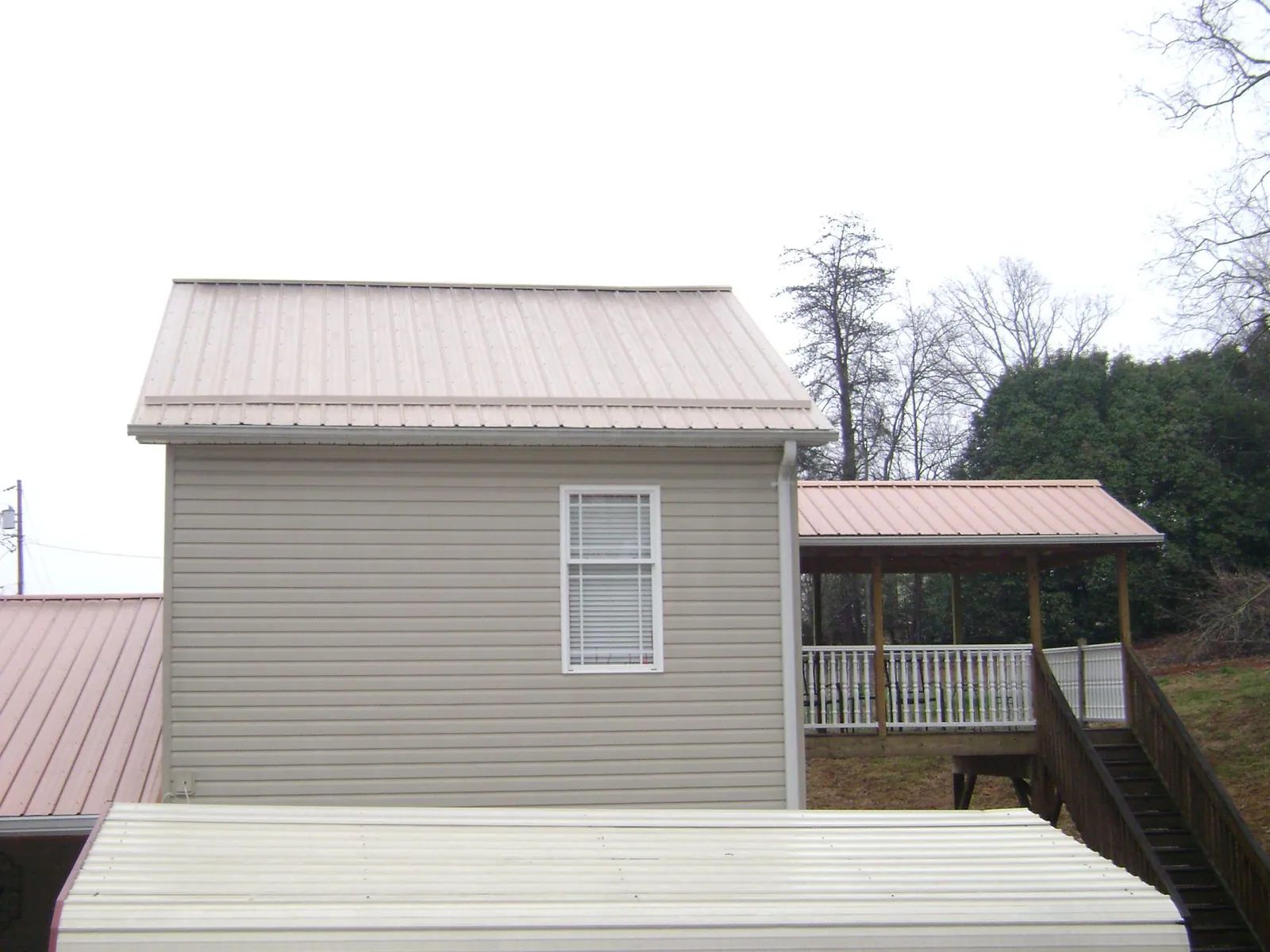 Tan metal roofs on a two story addition and attached porch, from a Roof Replacement job in Thorndale
